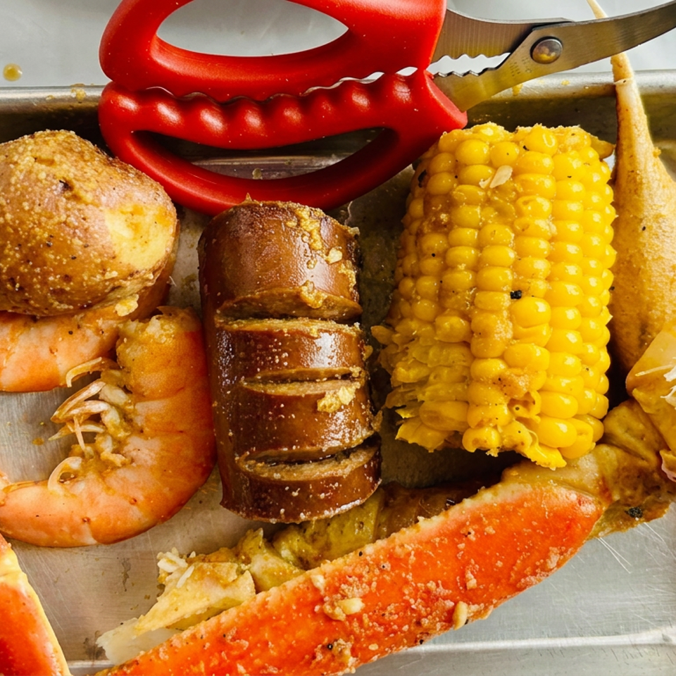 Seafood boil platter with crab legs, shrimp, lobster tail, corn on the cob, potato, and sausage in a metal tray.